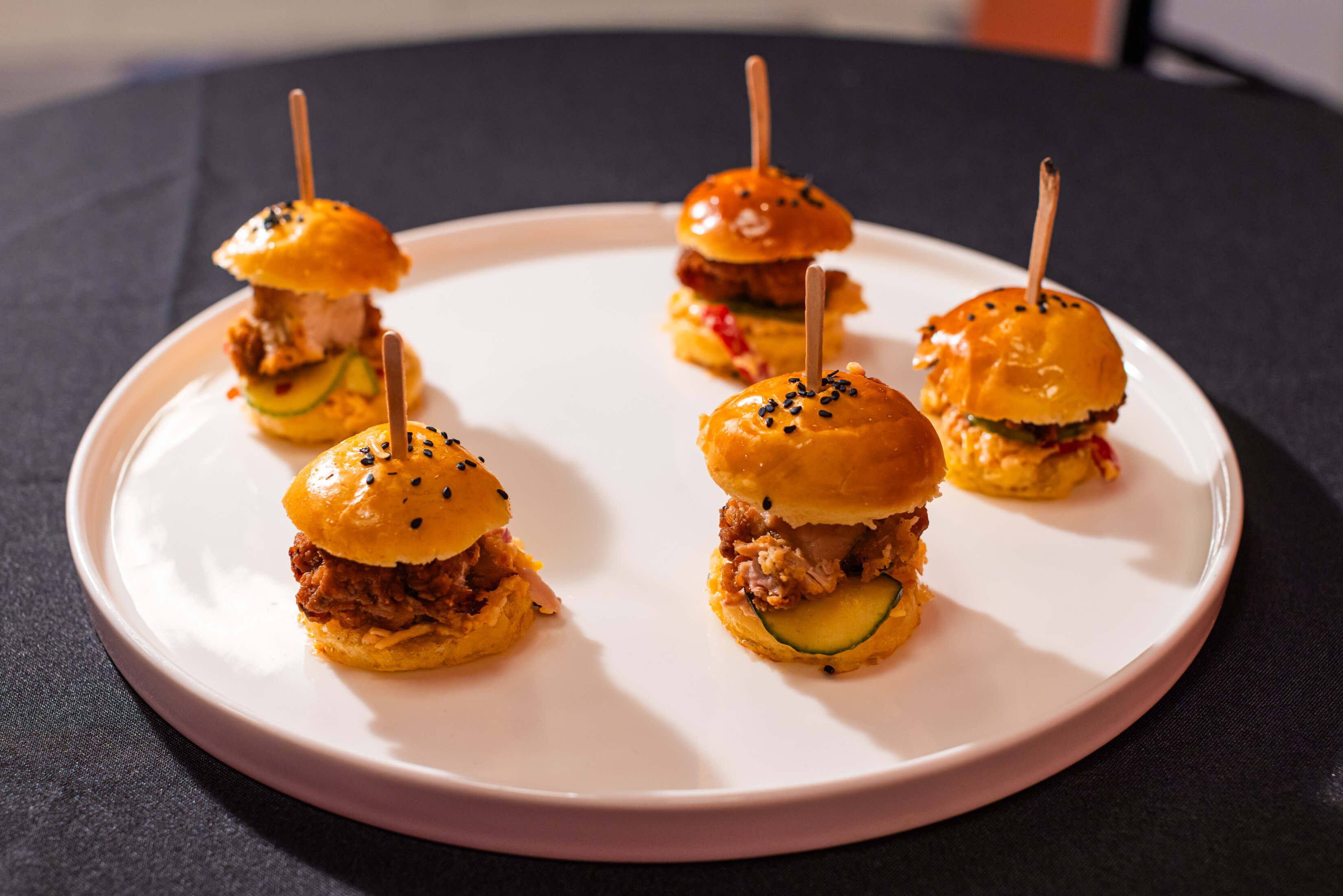 Five bite-sized burgers on a plate at an event in Museum of Illusions Las Vegas.