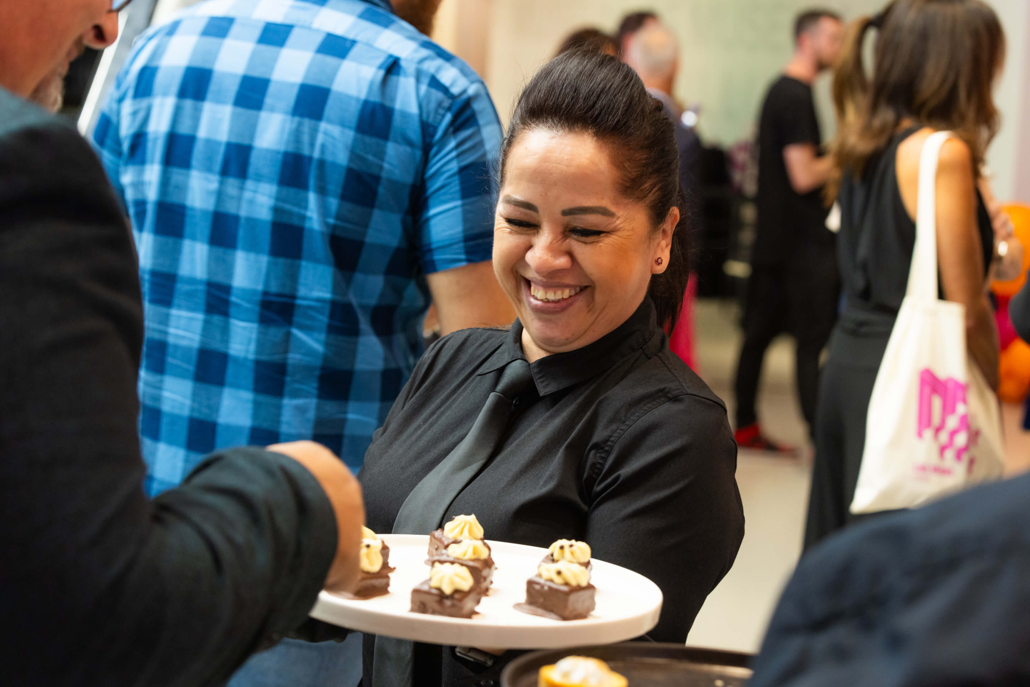 A smiling cateress is offering party food to a guest at an event in Museum of Illusions Las Vegas.